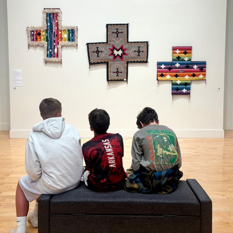 Three boys sitting in the museum.